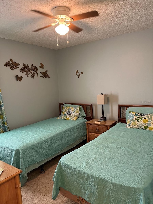 bedroom featuring ceiling fan, carpet floors, and a textured ceiling