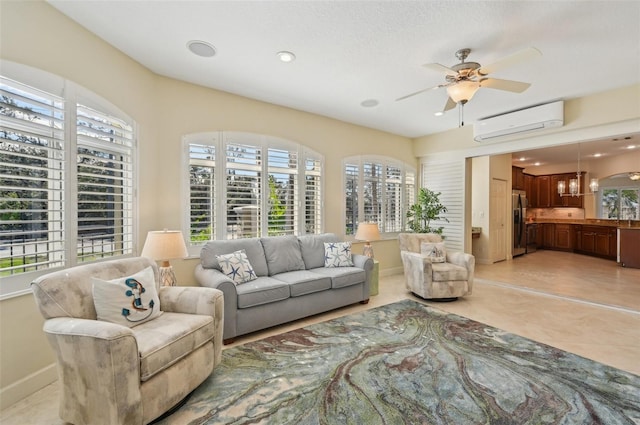 living room featuring light tile patterned flooring, an AC wall unit, and ceiling fan with notable chandelier