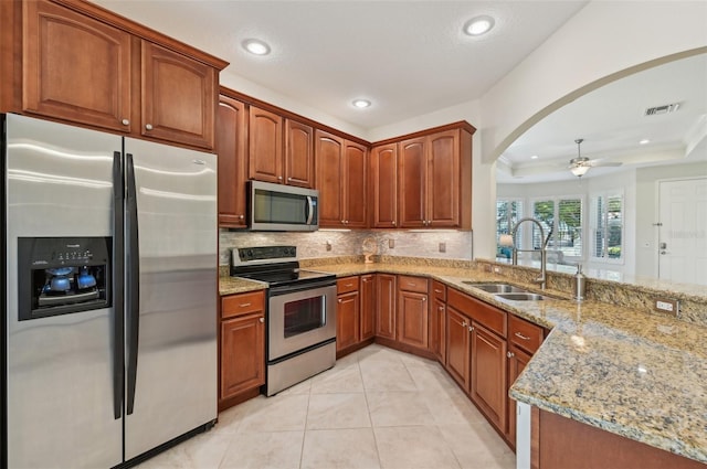 kitchen featuring sink, light tile patterned floors, appliances with stainless steel finishes, backsplash, and light stone countertops