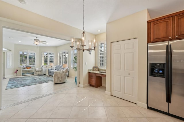 kitchen with light tile patterned flooring, built in desk, hanging light fixtures, ceiling fan, and stainless steel fridge with ice dispenser