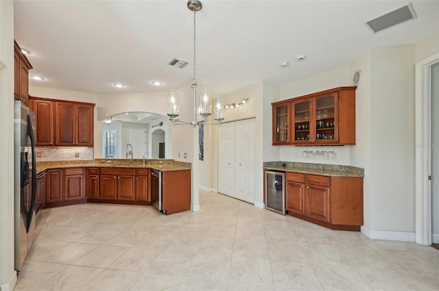 kitchen featuring sink, appliances with stainless steel finishes, wine cooler, light stone counters, and decorative light fixtures