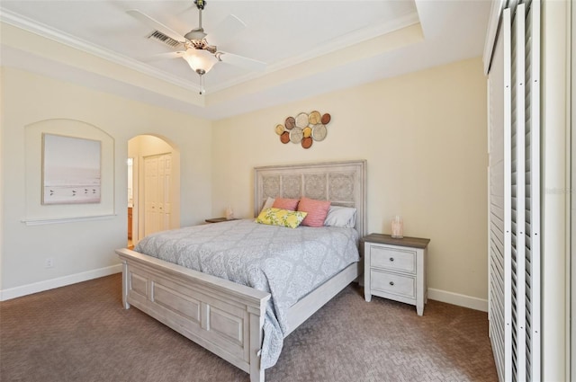 carpeted bedroom featuring ornamental molding, ceiling fan, and a tray ceiling