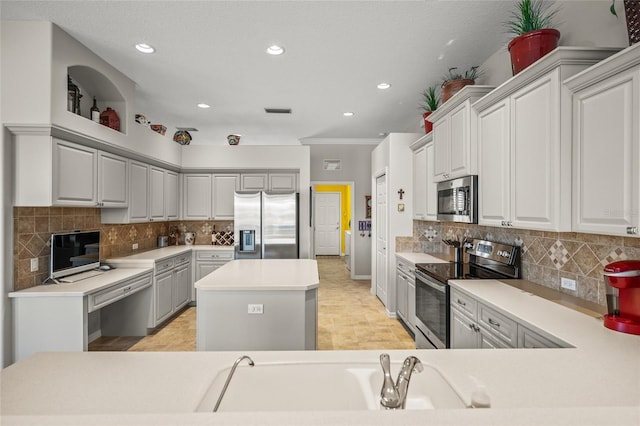 kitchen with tasteful backsplash, crown molding, appliances with stainless steel finishes, and gray cabinetry