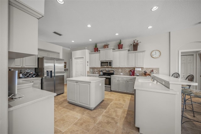 kitchen with a kitchen island, a breakfast bar, white cabinets, kitchen peninsula, and stainless steel appliances