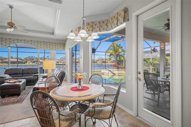 tiled dining area with a water view, ceiling fan, and a raised ceiling