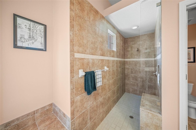 bathroom with toilet and a tile shower