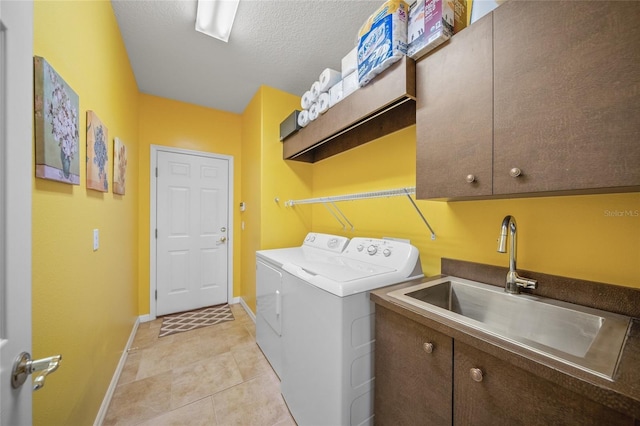 laundry room featuring sink, light tile patterned floors, cabinets, a textured ceiling, and separate washer and dryer