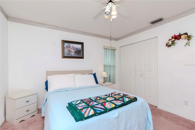 carpeted bedroom featuring ornamental molding, a closet, and ceiling fan