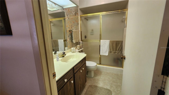 bathroom featuring vanity, toilet, and a shower with door