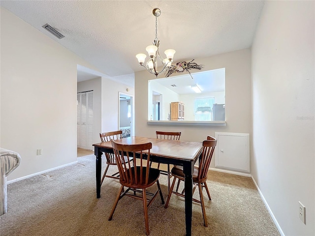 dining room featuring carpet flooring, a textured ceiling, and an inviting chandelier