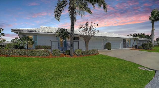 ranch-style home featuring a garage and a yard