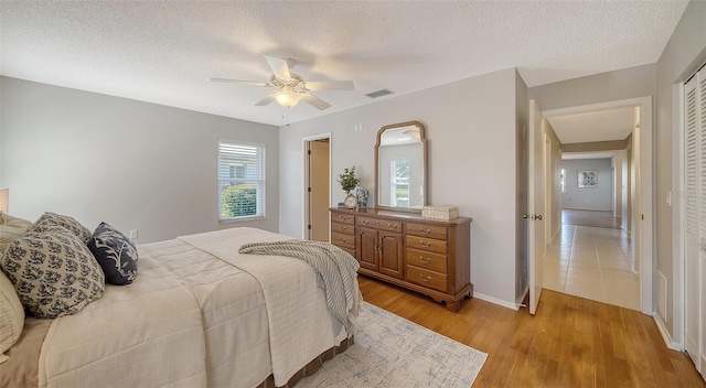 bedroom with multiple windows, a textured ceiling, and light wood-type flooring