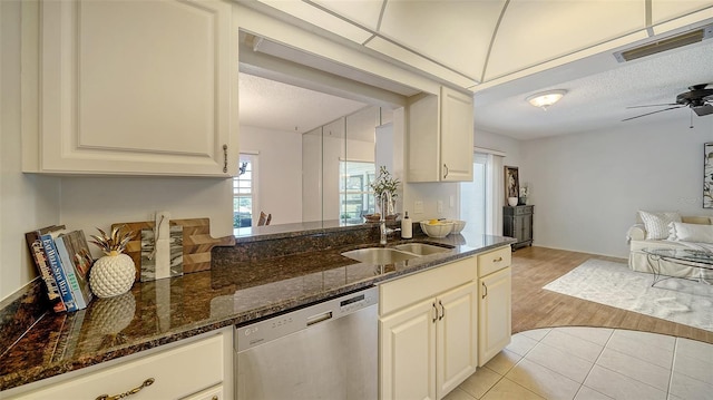 kitchen featuring sink, light tile patterned floors, dishwasher, ceiling fan, and dark stone countertops