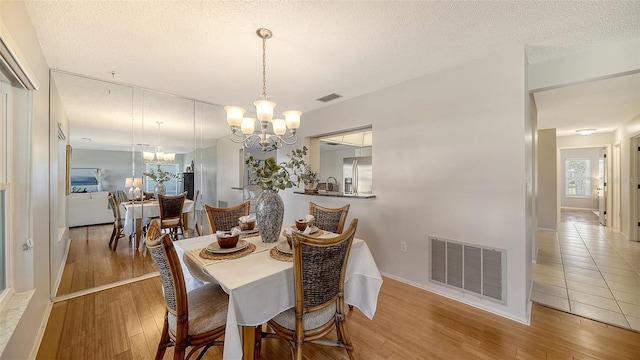 dining room with hardwood / wood-style floors, a notable chandelier, and a textured ceiling