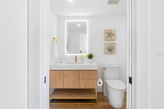 bathroom with wood-type flooring, toilet, and vanity