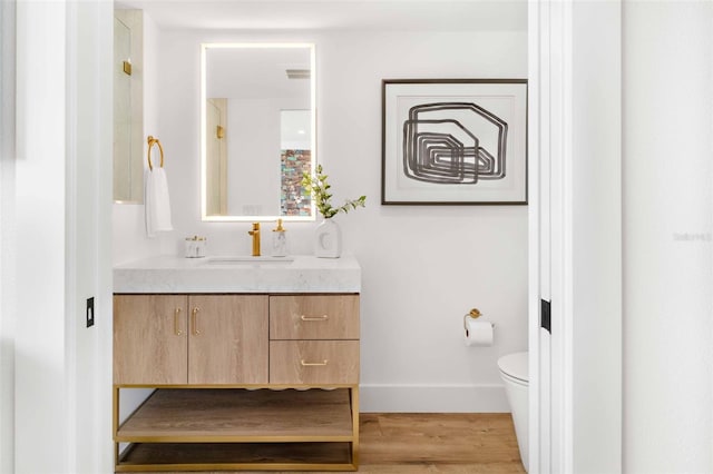 bathroom with hardwood / wood-style flooring, vanity, and toilet