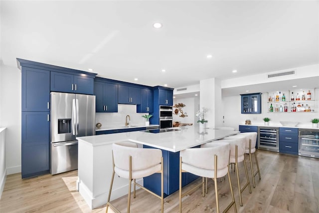 kitchen with sink, a breakfast bar area, stainless steel appliances, a spacious island, and beverage cooler