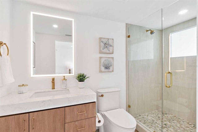 bathroom featuring vanity, toilet, and a shower with door