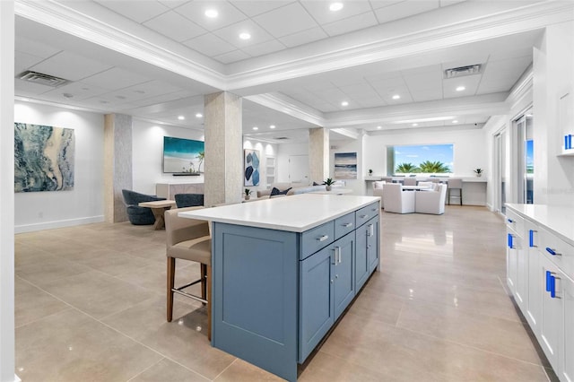 kitchen with white cabinetry, light tile patterned floors, a large fireplace, and a center island