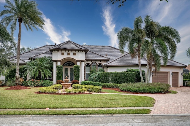 mediterranean / spanish house with a garage, a front yard, and french doors