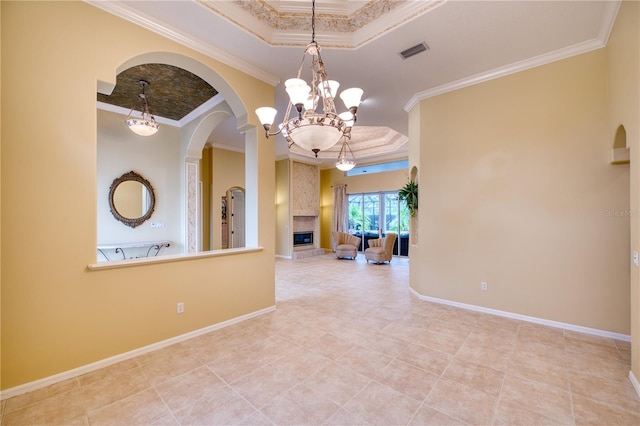 unfurnished room with crown molding, a notable chandelier, a fireplace, and a tray ceiling