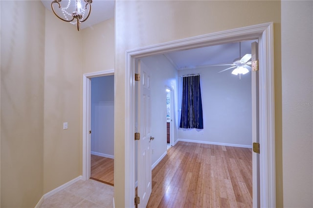 hallway with a notable chandelier and light wood-type flooring