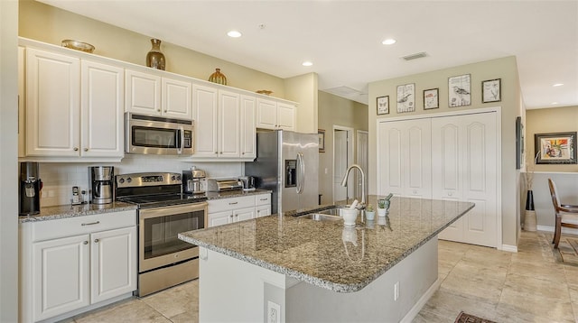 kitchen with a kitchen island with sink, sink, white cabinetry, and stainless steel appliances