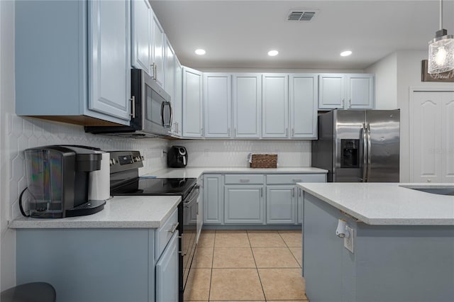 kitchen with light tile patterned flooring, stainless steel appliances, decorative light fixtures, and tasteful backsplash