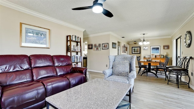 living room featuring ceiling fan with notable chandelier, ornamental molding, a textured ceiling, and light wood-type flooring