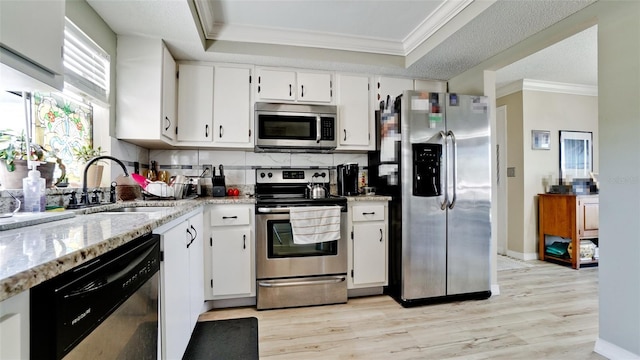 kitchen featuring stainless steel appliances, white cabinetry, sink, and a tray ceiling