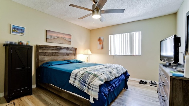 bedroom featuring ceiling fan, light hardwood / wood-style floors, and a textured ceiling