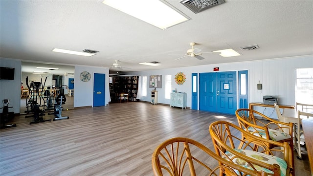 gym featuring hardwood / wood-style flooring, crown molding, a textured ceiling, and ceiling fan