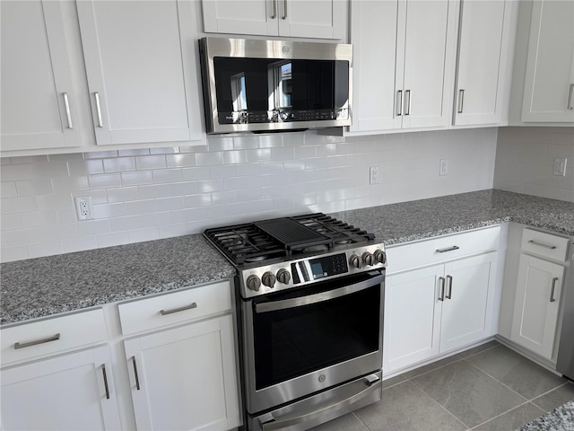 kitchen featuring white cabinetry, appliances with stainless steel finishes, light tile patterned flooring, and light stone countertops