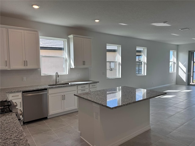 kitchen featuring gas stove, open floor plan, white cabinetry, a sink, and dishwasher