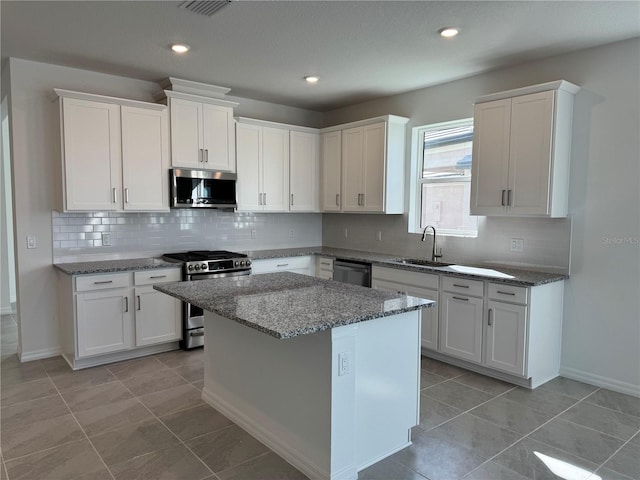 kitchen with appliances with stainless steel finishes, a sink, and white cabinets