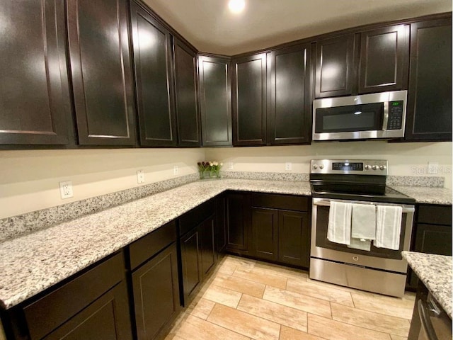 kitchen with light stone countertops, dark brown cabinets, and stainless steel appliances