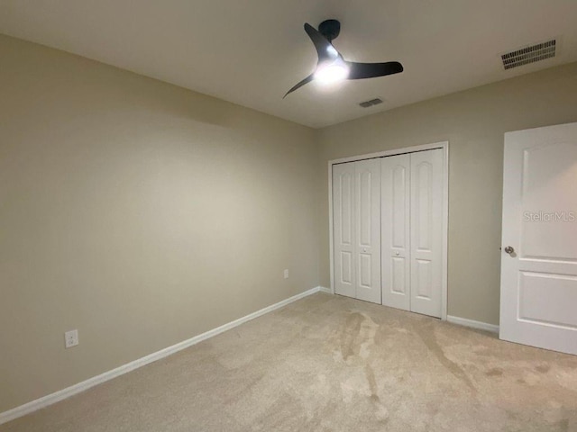 unfurnished bedroom featuring ceiling fan, light colored carpet, and a closet