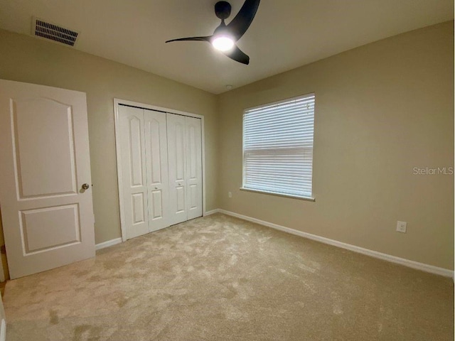 unfurnished bedroom with light carpet, ceiling fan, and a closet