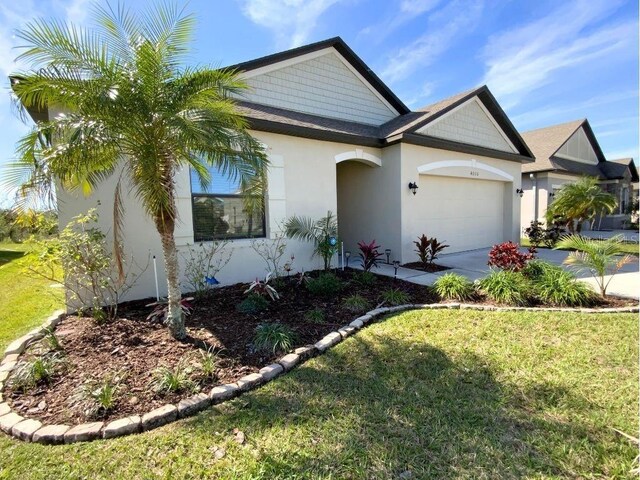 view of front of home with a garage, a front lawn, concrete driveway, and stucco siding