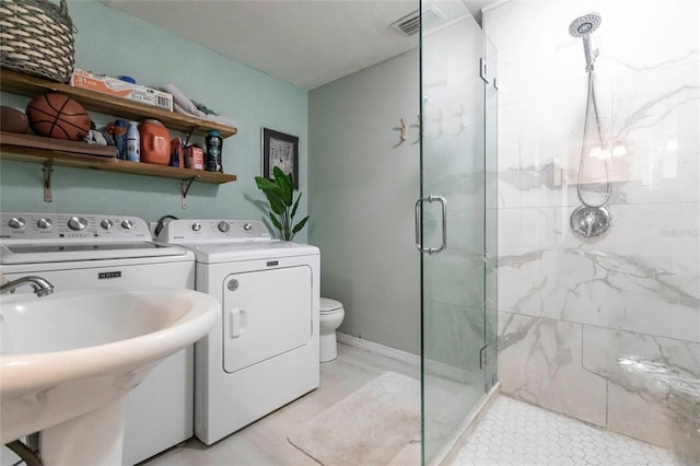 bathroom featuring toilet, independent washer and dryer, sink, and a shower with door