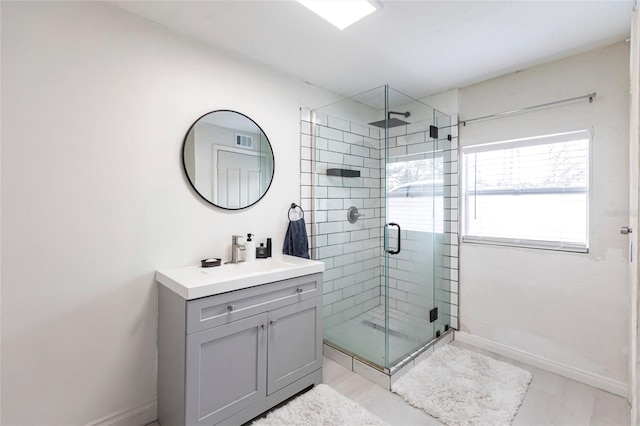 bathroom featuring a shower with door and vanity