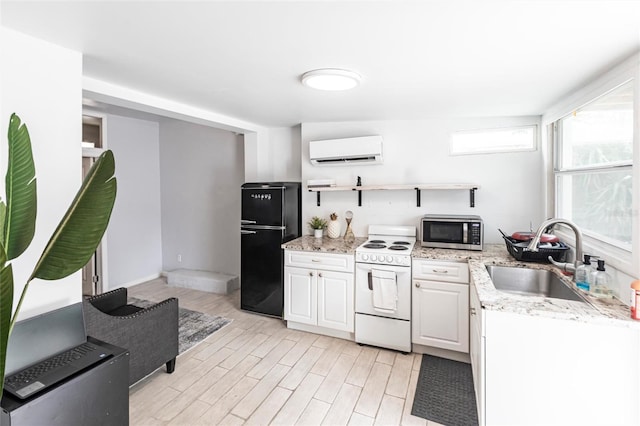 kitchen with electric stove, sink, black refrigerator, a wall unit AC, and white cabinets