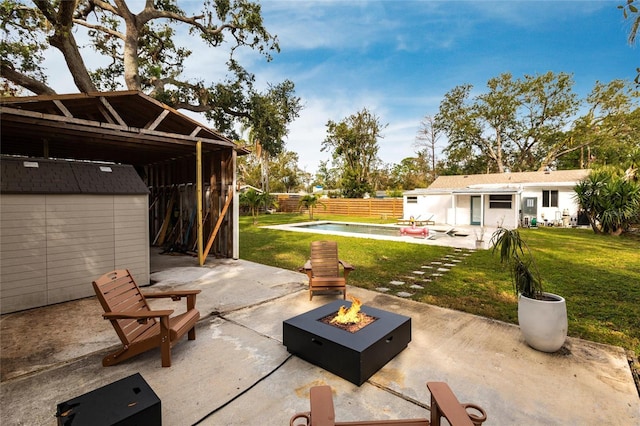 view of patio with a fenced in pool, a shed, and an outdoor fire pit