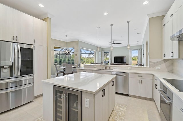 kitchen featuring wine cooler, sink, decorative light fixtures, a center island, and appliances with stainless steel finishes