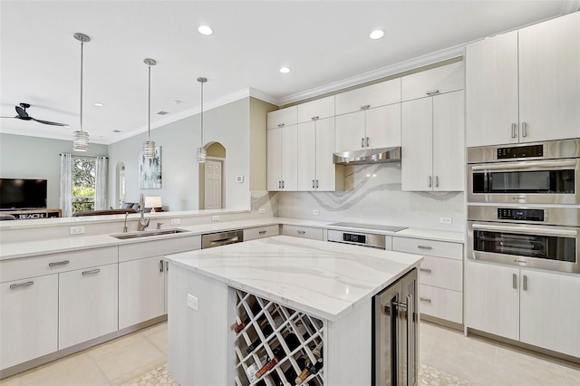 kitchen with appliances with stainless steel finishes, pendant lighting, sink, wine cooler, and a center island