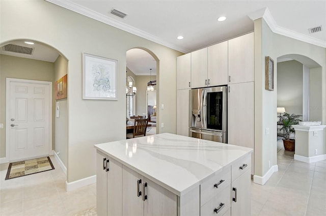 kitchen with white cabinetry, crown molding, stainless steel fridge, and a center island