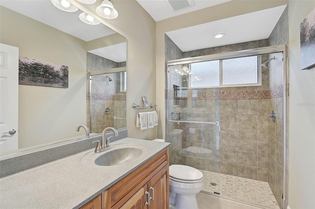 bathroom featuring tile patterned floors, vanity, toilet, and a shower with shower door