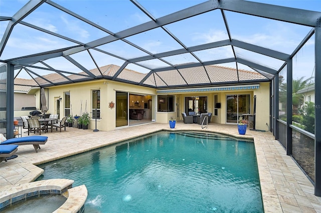 view of pool with an in ground hot tub, glass enclosure, and a patio area