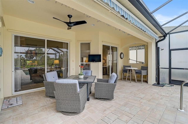 view of patio with ceiling fan and glass enclosure