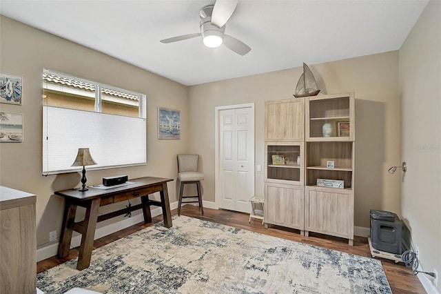 office with ceiling fan, dark hardwood / wood-style floors, and a wood stove